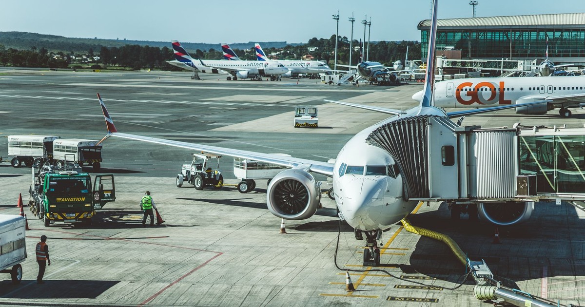 A scenic view of airplanes at an airport runway during a busy day, ready for boarding.
