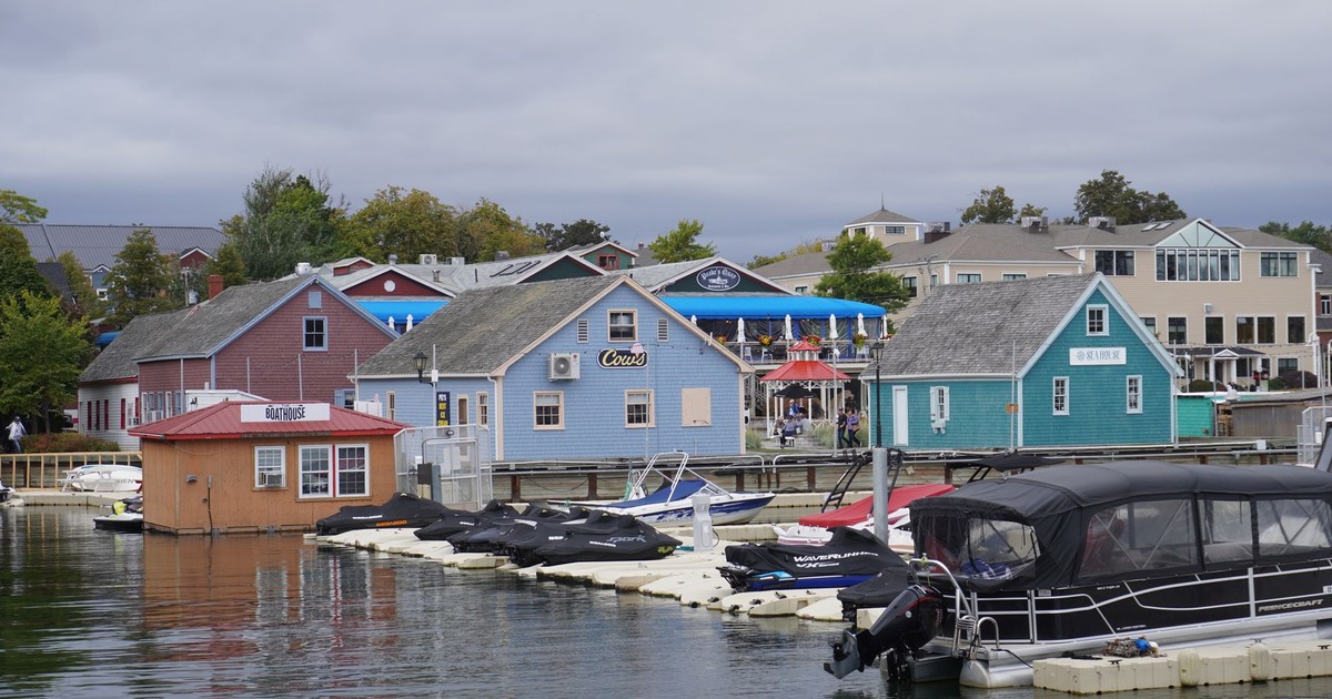 Scenic view of a marina with colorful boathouses and boats on a cloudy day.