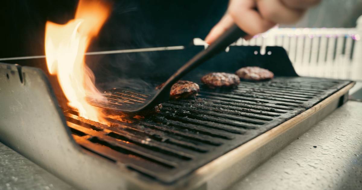 Close-up view of juicy burgers sizzling on a flaming outdoor grill.
