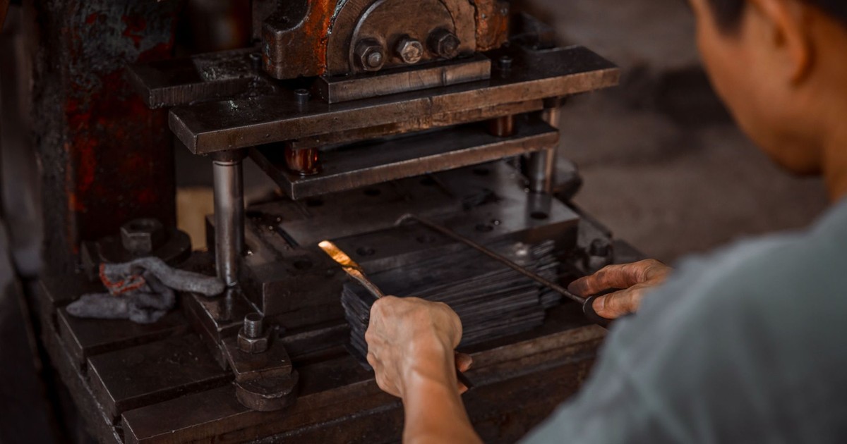 Close-up of worker using industrial press in metalworking process.