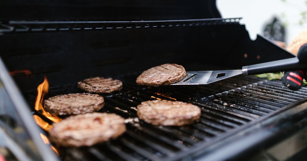 Close-up of beef patties grilling on an outdoor barbecue. Perfect for summer cookouts.
