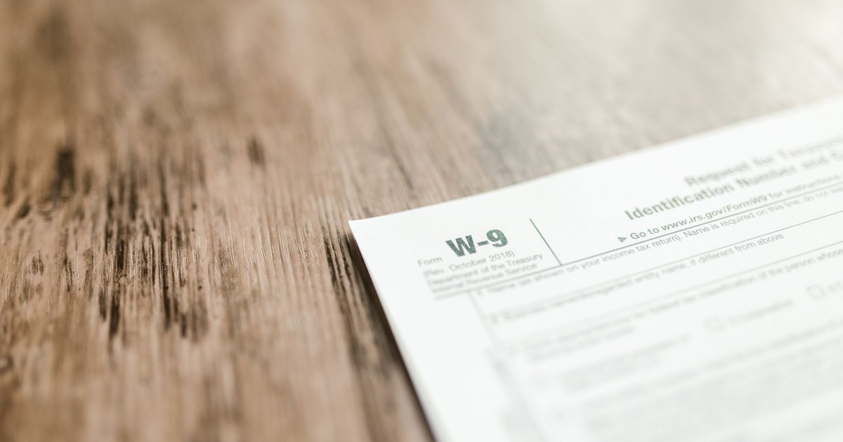 A close-up of a W-9 tax form placed on a wooden desk, emphasizing paperwork and finance.
