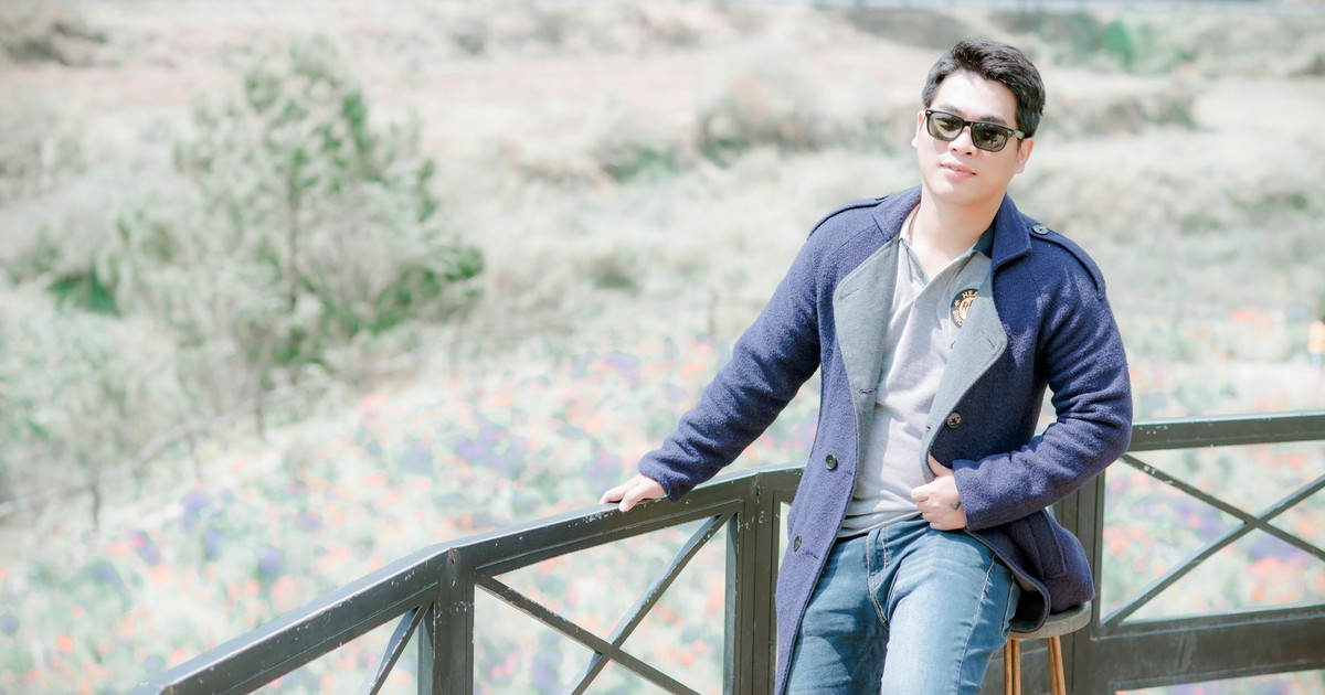 A stylish young man wearing sunglasses and a jacket poses casually outdoors, capturing a relaxed vibe.