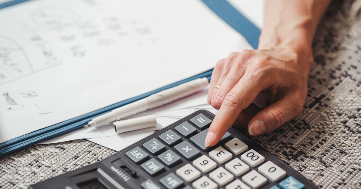 A hand using a calculator on top of documents, indicating financial calculation or analysis.