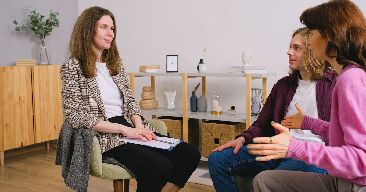 Young adults discuss with a counselor during an indoor therapy session.