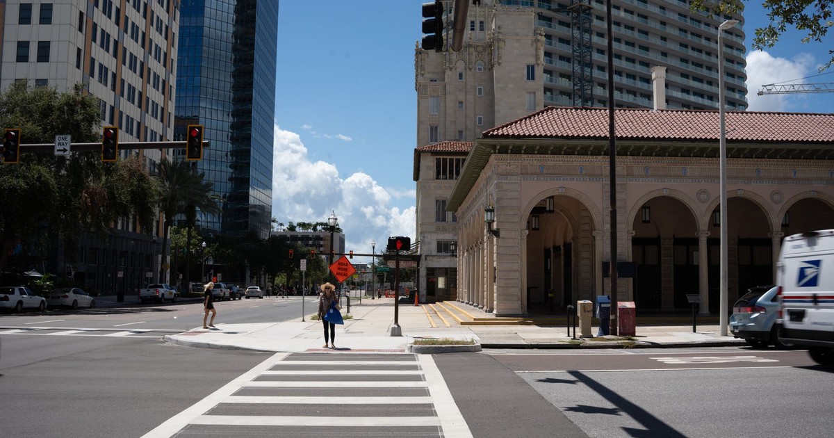 Street scene with historic building, modern skyscrapers, and pedestrians crossing at an intersection.