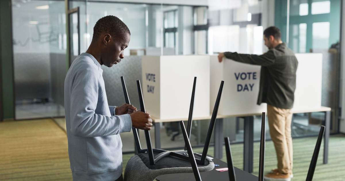 Men preparing voting booths indoors for election day, enhancing democracy.