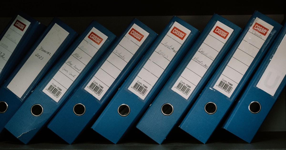 Neatly arranged blue office binders labeled with dates and names for organized storage.