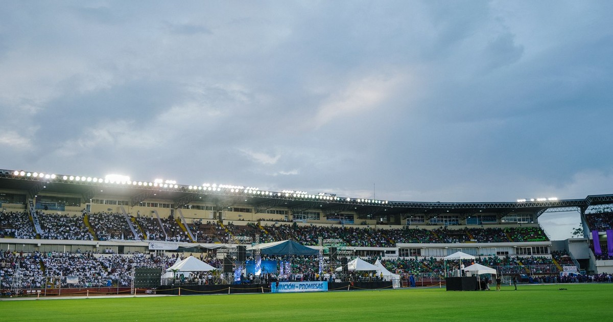 Large illuminated stadium filled with spectators on a cloudy day, ideal for sports or concert events.