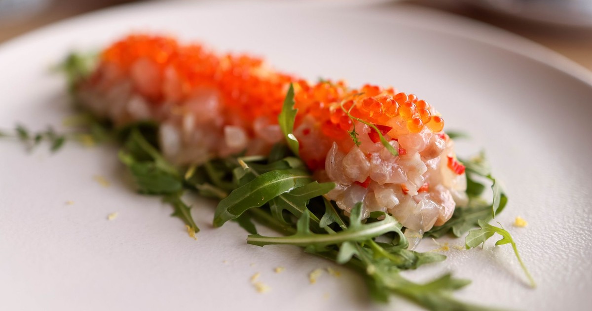 Elegant salmon tartare with arugula and roe on a white plate, perfect for fine dining concepts.
