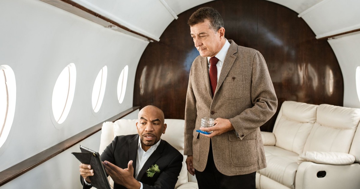 Two businessmen discussing plans inside a luxurious private jet.