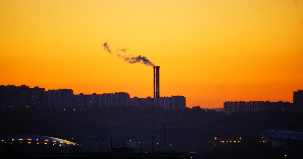City skyline at sunset with a smokestack, highlighting environmental urban scenes.
