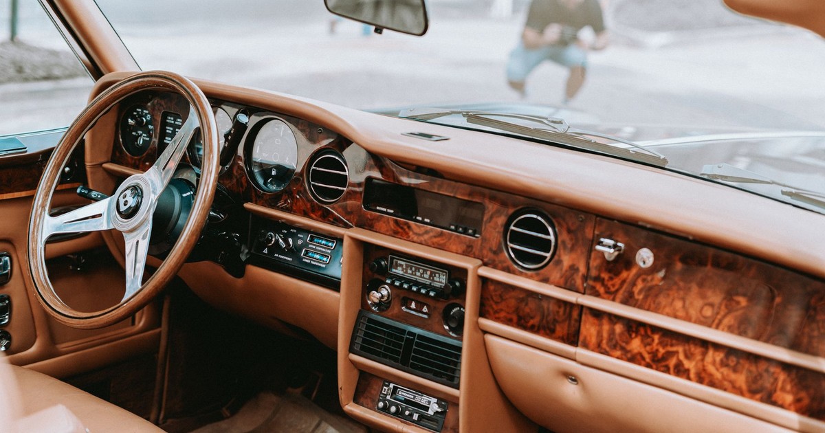 Explore the opulent wooden dashboard and leather seats of a vintage luxury car interior.