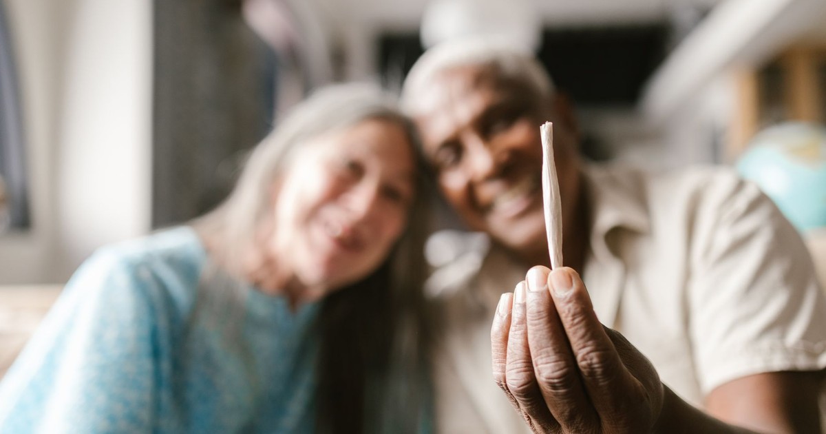 Joyful senior couple enjoying cannabis culture indoors.