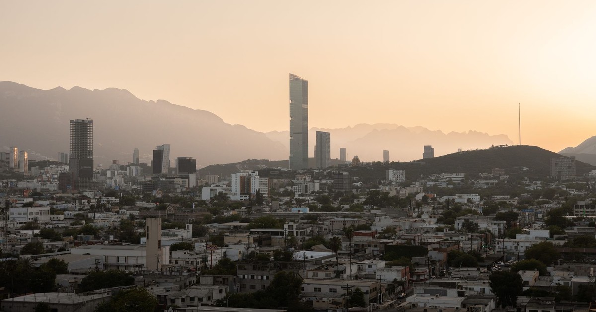 Aerial view of Monterrey's skyline at sunset, featuring modern skyscrapers and mountains.