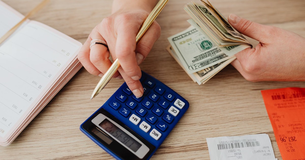 Hands handling cash and calculator for budget planning. Modern financial scene.
