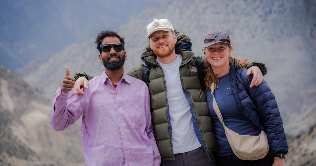 Three friends enjoying a scenic view in Lo Manthang, Nepal, with a mountainous backdrop.