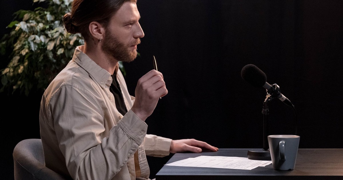 A man recording a podcast in a professional studio environment, engaging with a microphone.