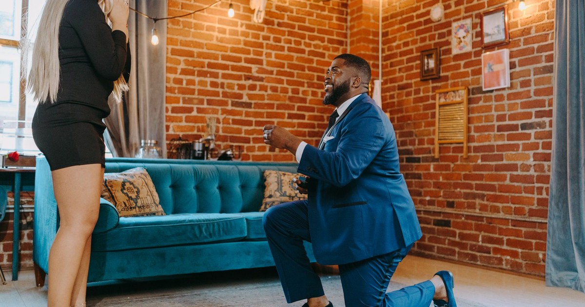 A man proposes to a woman indoors, capturing a romantic and intimate moment.