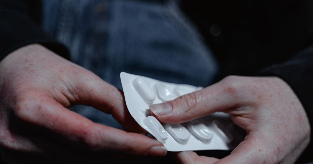 Person holding a blister pack of medication, highlighting health and treatment themes.