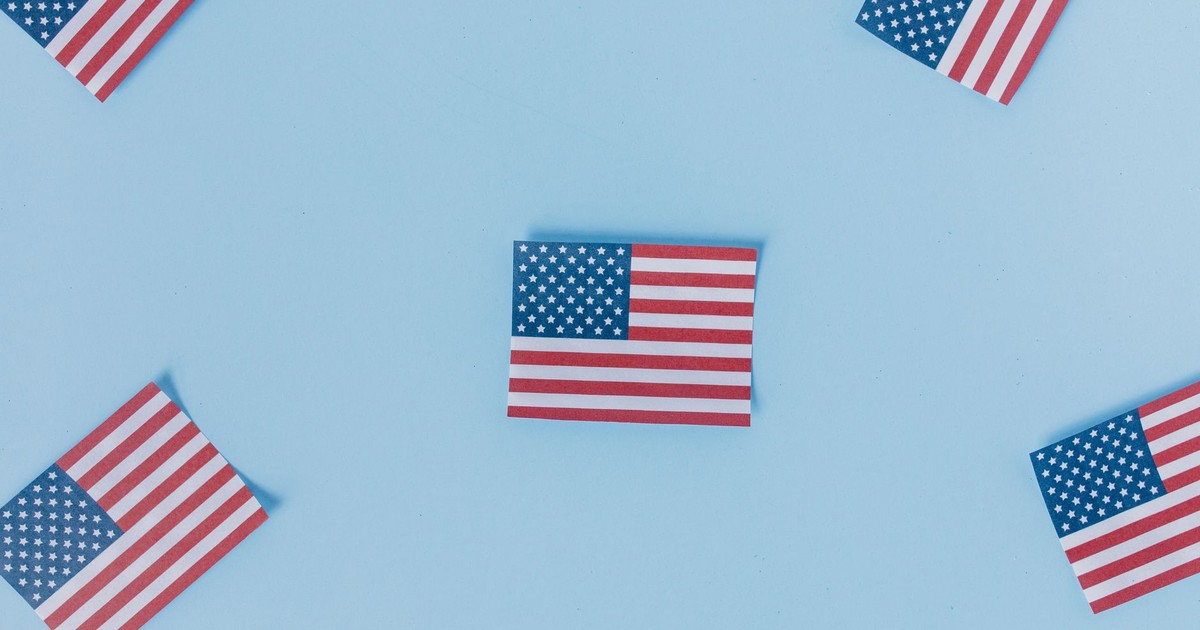 Multiple American flags arranged on a pastel blue background for a patriotic theme.