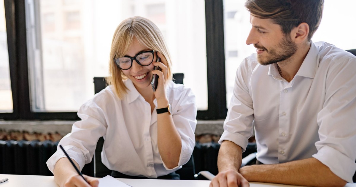 Two colleagues collaborate in a bright office, sharing ideas and notes.
