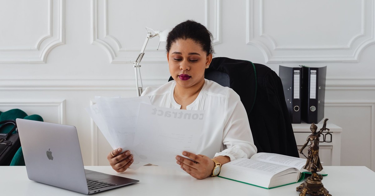 Confident businesswoman analyzing contracts at her clean, organized desk.