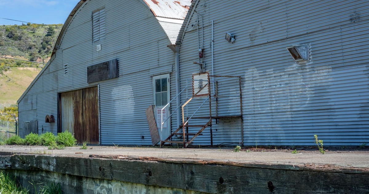 Exterior view of an abandoned industrial building with corrugated iron and rusty surfaces.