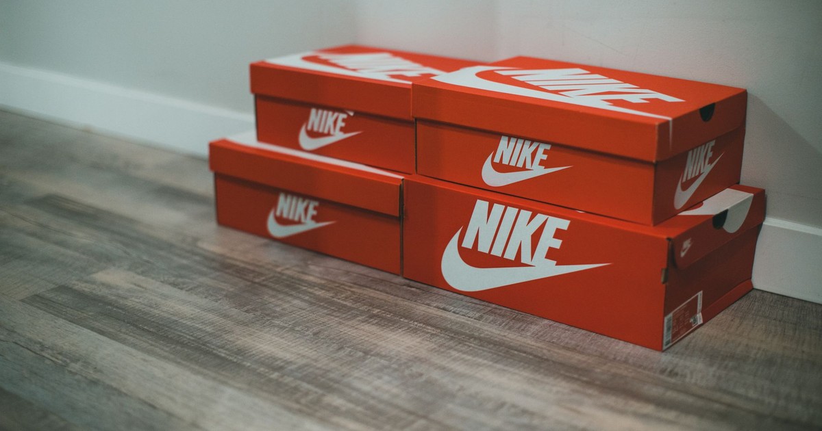 Red Nike shoe boxes stacked neatly on a wooden floor indoors.