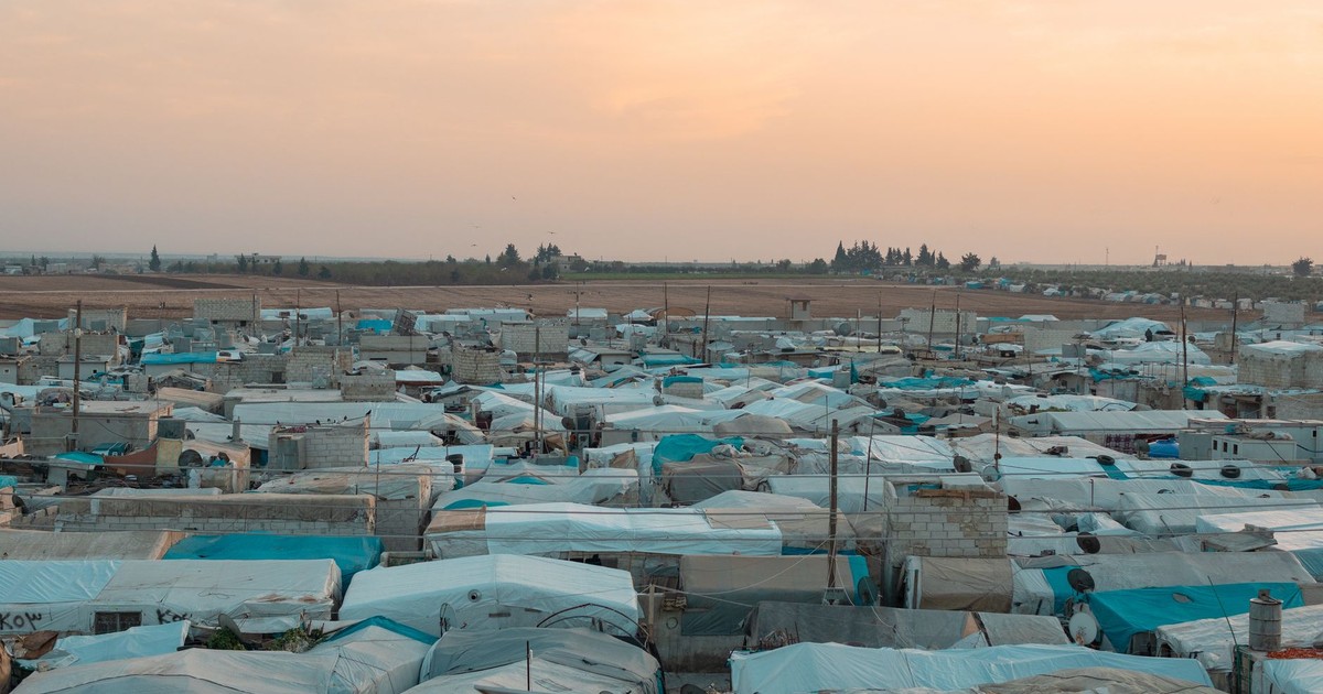 Aerial photo of a sprawling refugee camp under a vibrant sunset sky