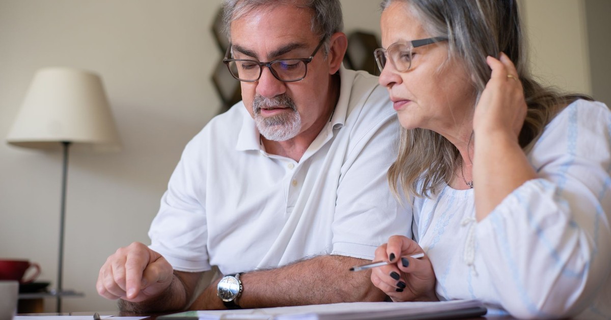 Elderly couple enjoying leisure time with crosswords at home, showcasing togetherness.