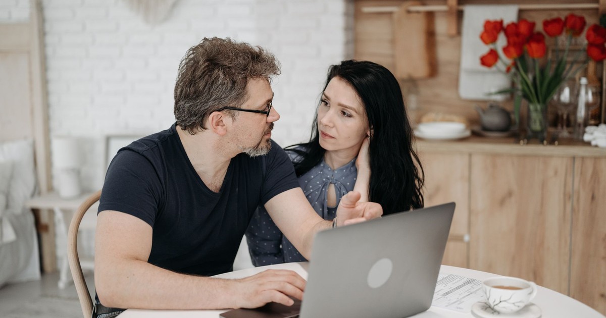 A couple engaged in discussion while using a laptop at a cozy home setting.