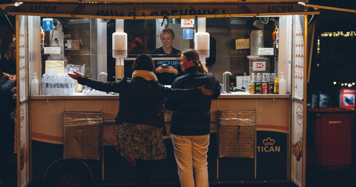 Women buying food at a street stand at night in Copenhagen, Denmark.