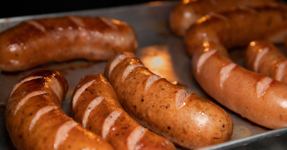 A close-up of juicy grilled sausages on a metal tray, perfect for food lovers.