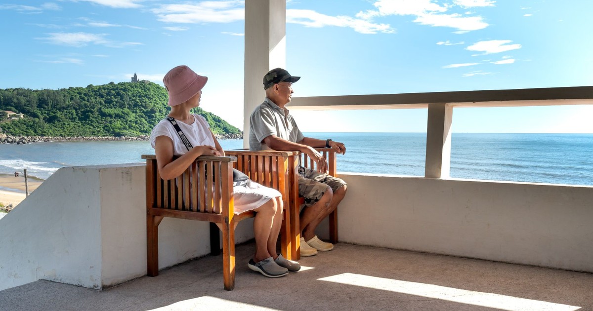 Senior couple sitting on balcony chairs, enjoying a relaxing ocean view in summer.