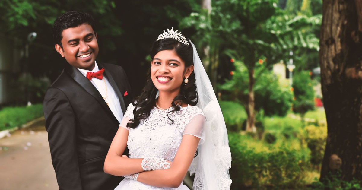Joyful bride and groom posing outdoors in elegant attire at their wedding.