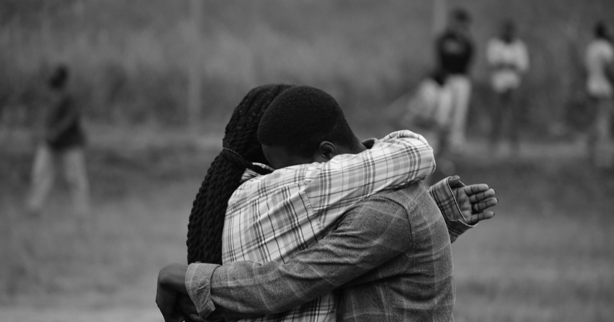 Two people hug in a heartfelt moment captured in monochrome outdoors.