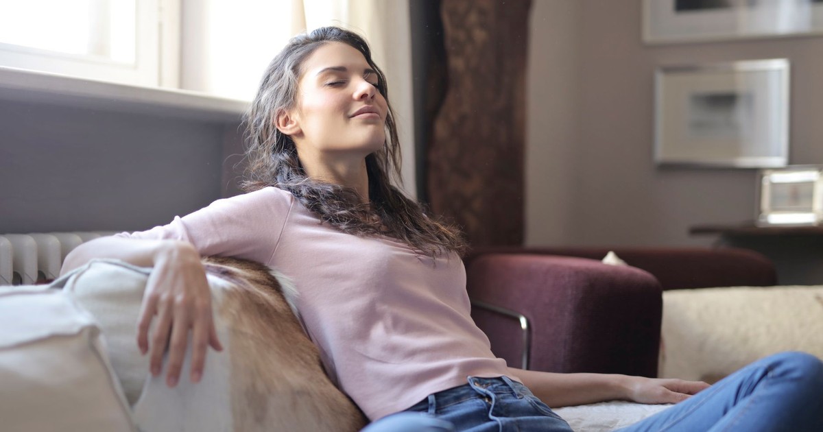 Woman relaxing on a couch in a cozy living room, embodying tranquility and comfort.