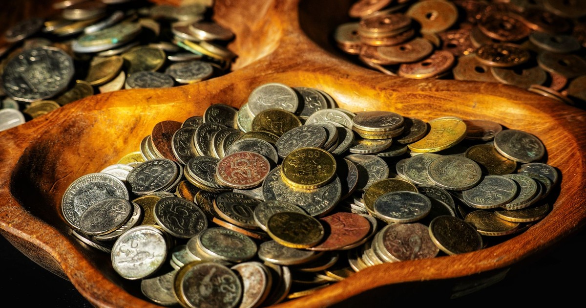 Indonesian coins of various denominations displayed in wooden bowls, showcasing currency diversity.