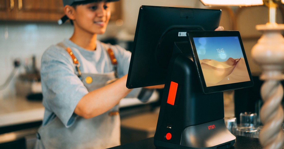 A cashier using a modern point of sale terminal in a store.