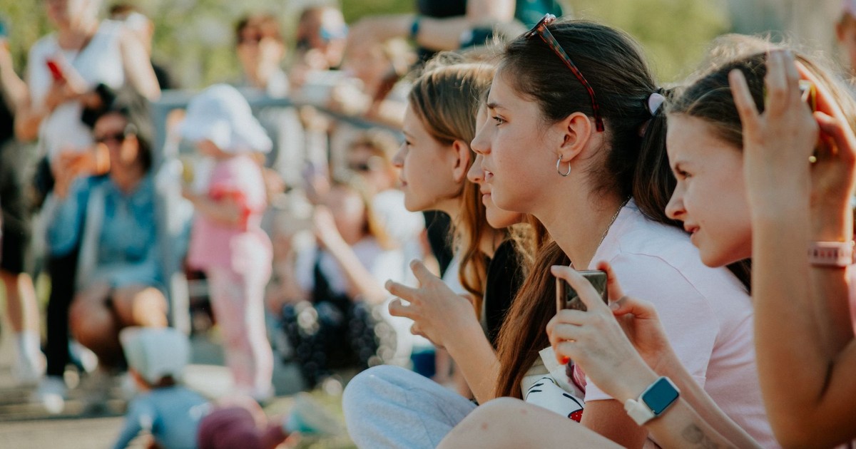 Group of teenagers enjoying an outdoor summer event filled with people and activities.