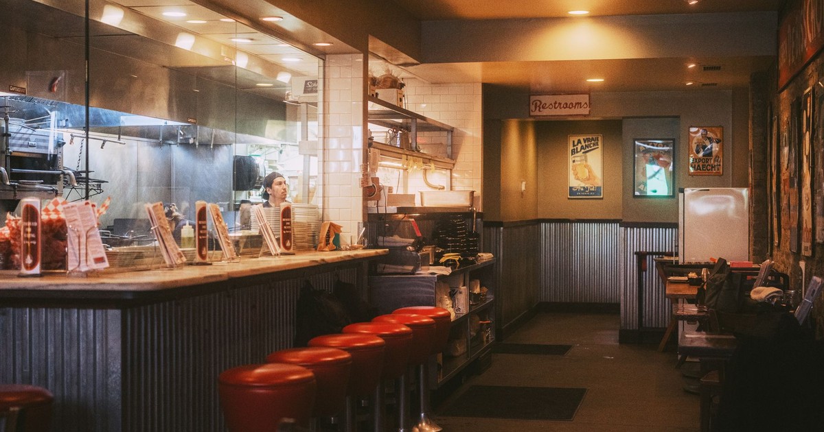 Warm and inviting interior of a classic American diner with red stools and open kitchen.