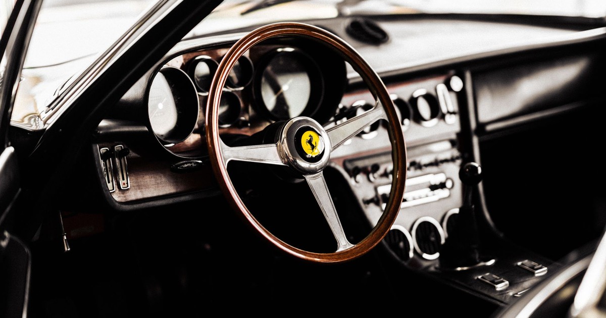 A detailed view of a vintage Ferrari interior showcasing a wooden steering wheel and classic dashboard design.