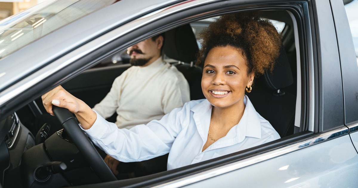 African American woman happily test driving a new car at a dealership. Capturing her joyful expression.