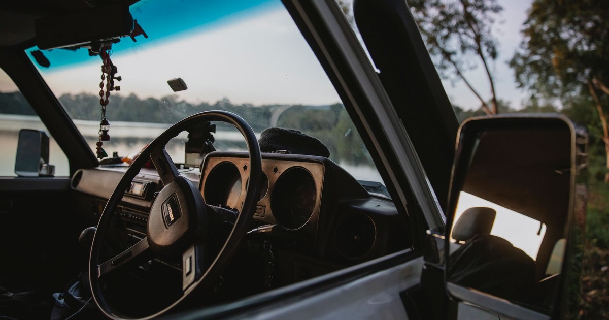 Details of modern car parked near lush green trees on lake shore during road trip in nature