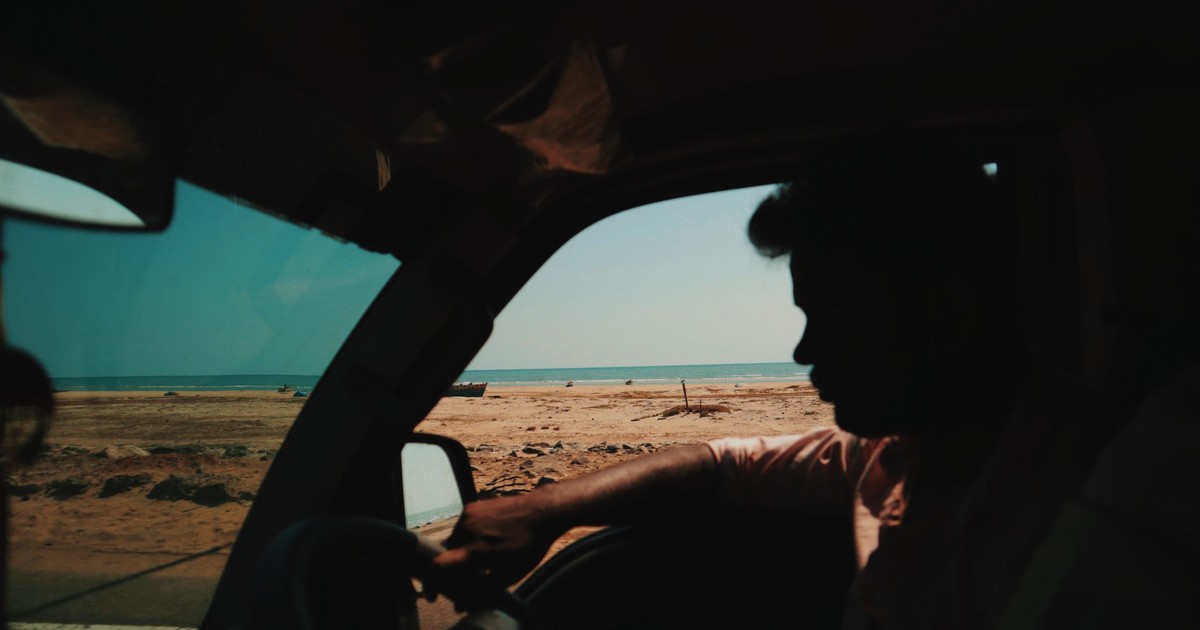 Silhouette of a man driving by a serene beach, capturing coastal tranquility and adventure.