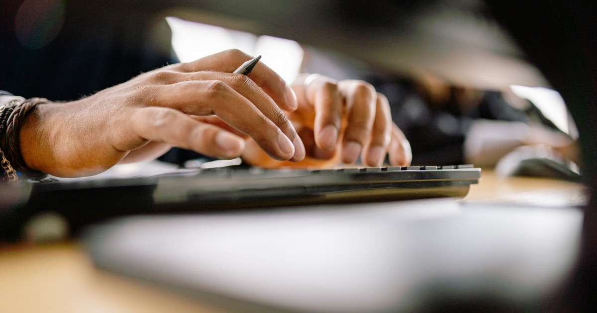 A detailed view of a person typing on a keyboard, emphasizing productivity and office work.