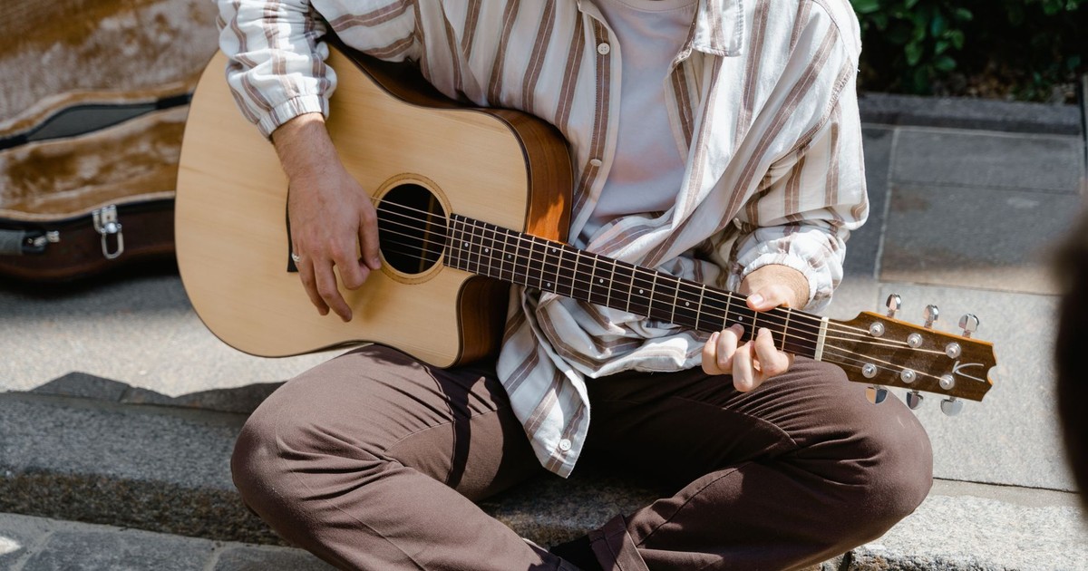 A man plays acoustic guitar on a street, creating a peaceful atmosphere.