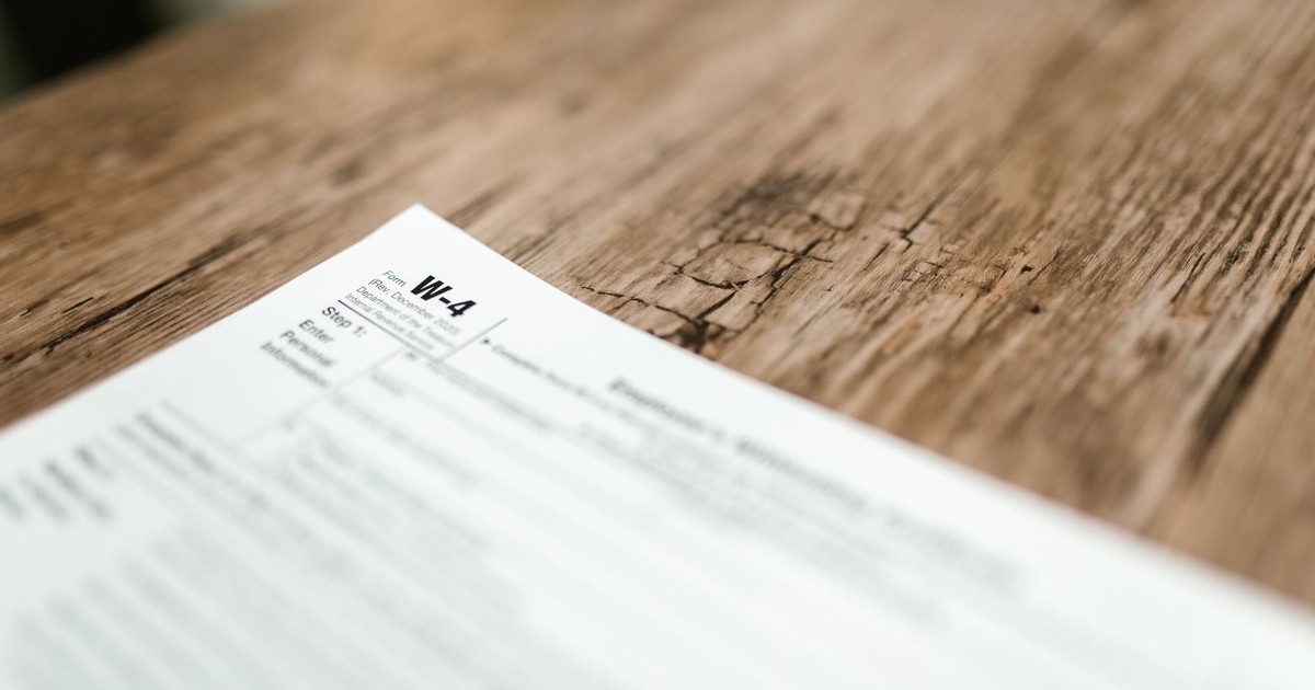 Close-up of a W-4 form resting on a rustic wooden table, highlighting textures.