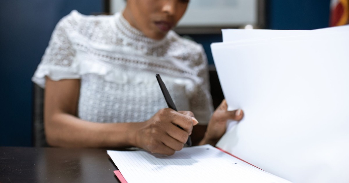 African American woman signing documents in an elegant office setting, showcasing leadership.